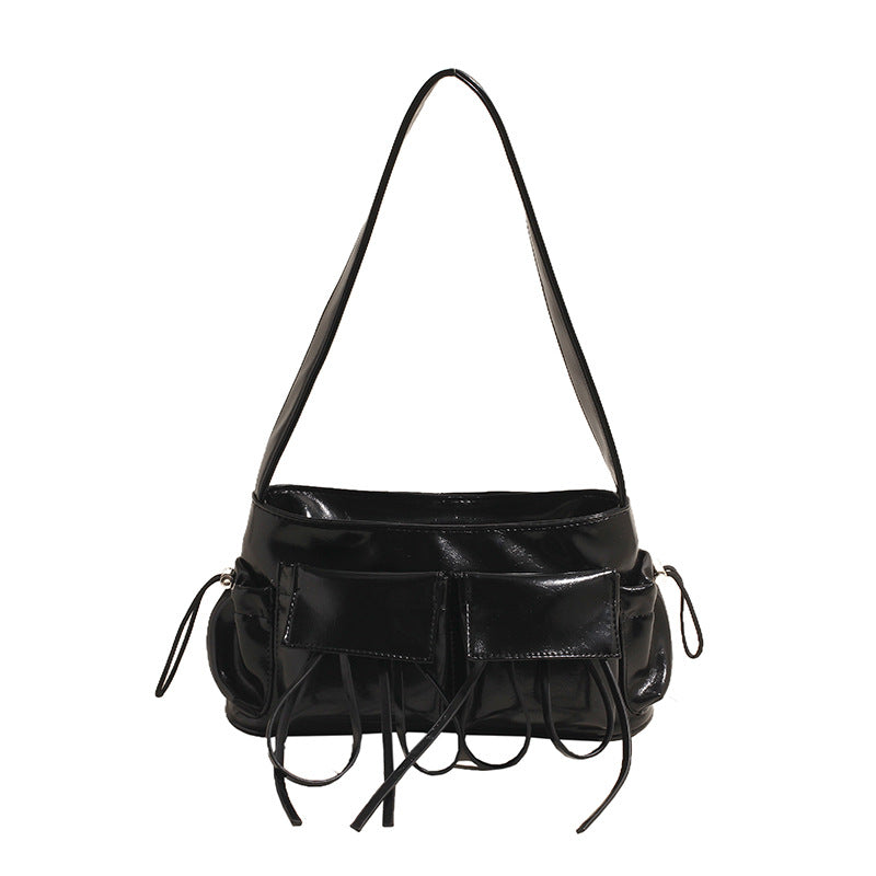 Sac baguette noir verni à poches plaquées et liens noués, vu de face, bandoulière courte tendue