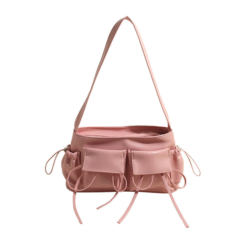 Rose poudré et souple, le sac baguette de face aligne ses deux poches plaquées et ses liens noués