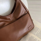 Gros plan du cuir végan marron, surpiqûre horizontale et patte estampée près de la couture