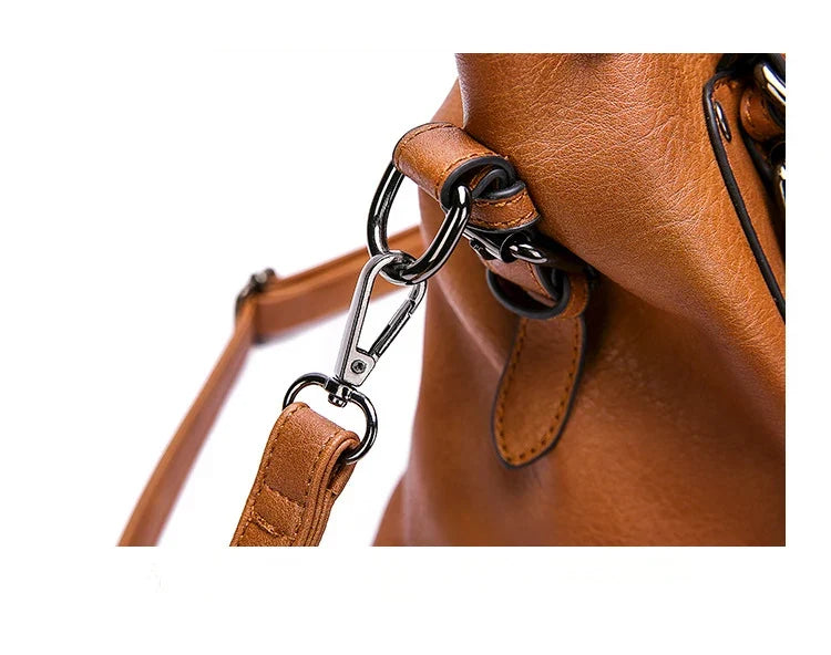 Gros plan sur le mousqueton et l'anneau métal reliant la bandoulière matelassée au sac caramel