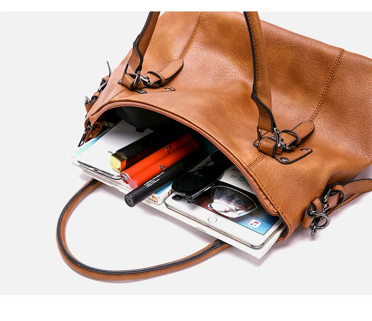 Contenu du sac ouvert : cahiers, stylos et tablette glissés dans le grand compartiment caramel