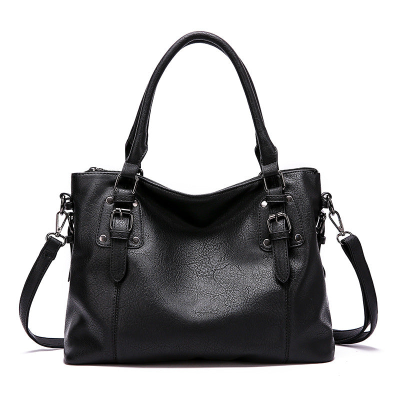 Cabas noir en cuir végan souple, de face, doubles anses, boucles latérales et bandoulière amovible
