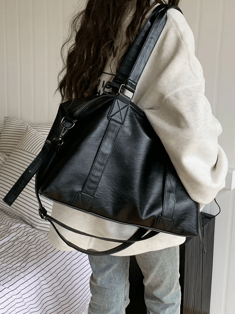 Volumineux sur l'épaule d'un modèle vu de dos en jean, le sac noir descend jusqu'au bas du dos