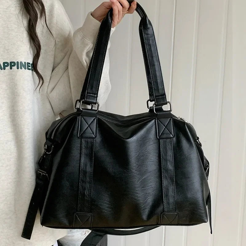 Tenu à bout de bras par un modèle en sweat crème, le grand sac noir laisse voir toute sa largeur