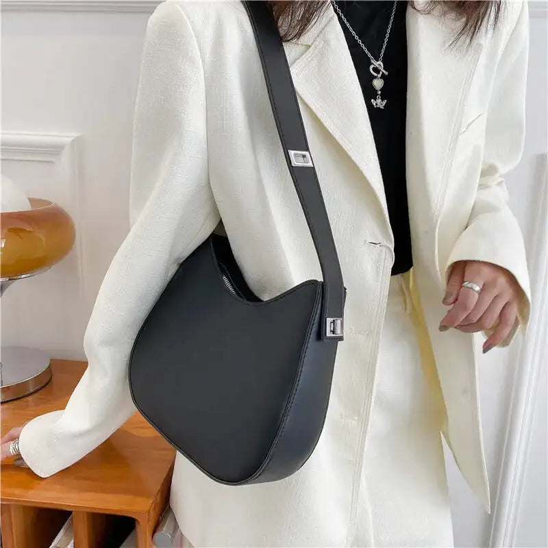Croisé sur un blazer blanc écru, le hobo noir et sa sangle réglable barrant le buste