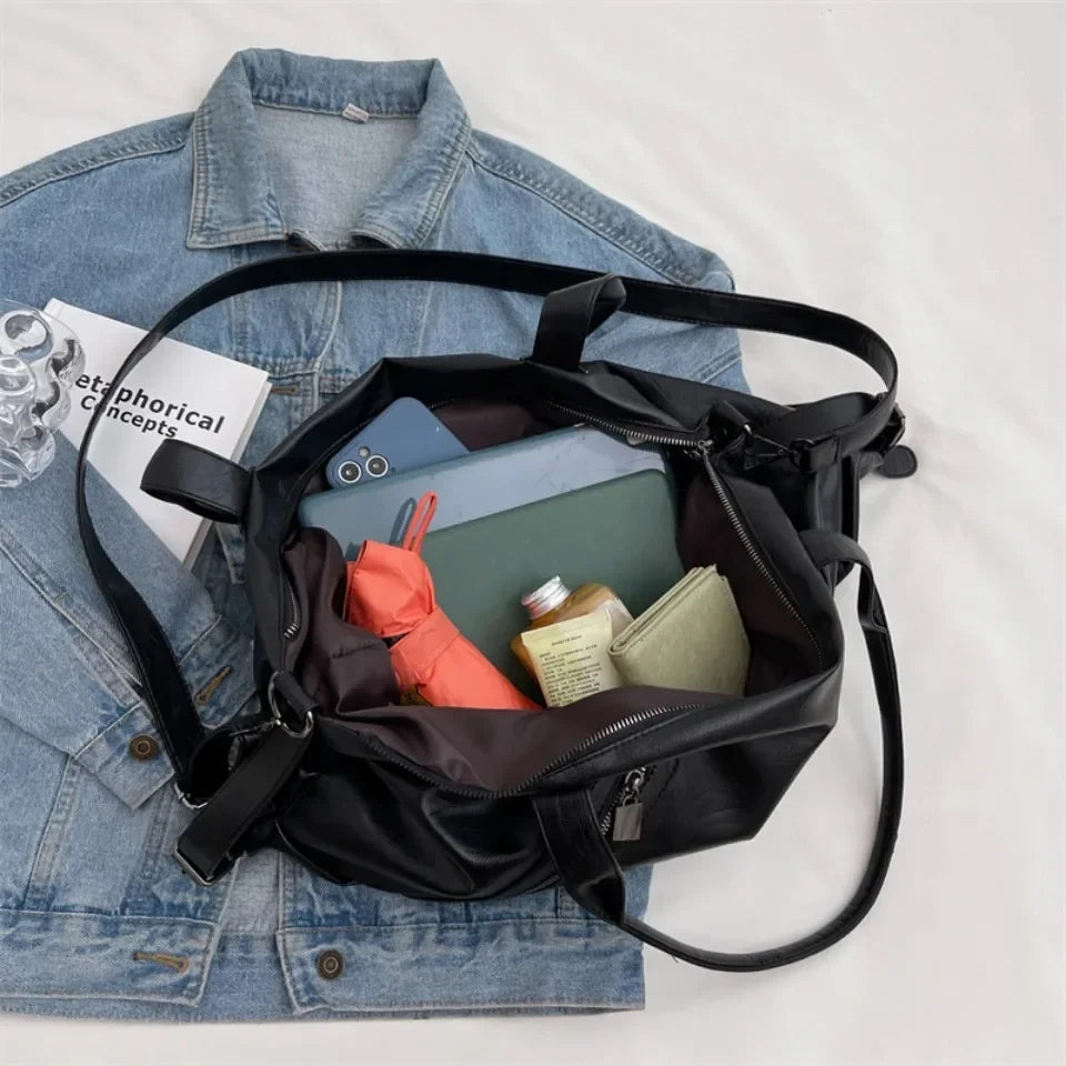 Le sac noir ouvert laisse voir un ordinateur portable, un téléphone, un parapluie et un portefeuille