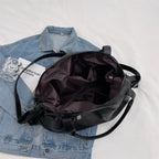 Intérieur doublé largement ouvert sur une veste en jean, poche plaquée et sangle bandoulière noire