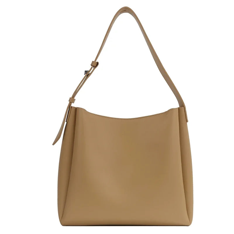 Beige camel pour ce sac seau souple, sangle large réglable et silhouette arrondie, vu de face