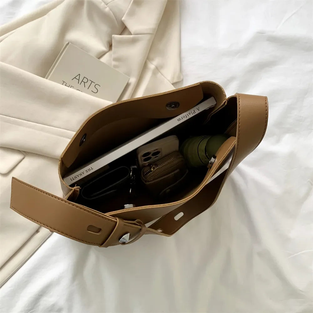 Ouvert sur un drap blanc, le sac camel laisse voir un ordinateur portable et des écouteurs