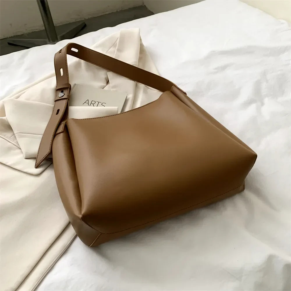Posé sur un drap froissé, le hobo camel montre son soufflet et sa sangle réglable de trois quarts