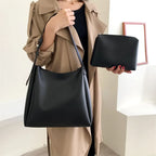 Silhouette en trench beige portant le hobo noir à l'épaule, pochette assortie tenue à la main