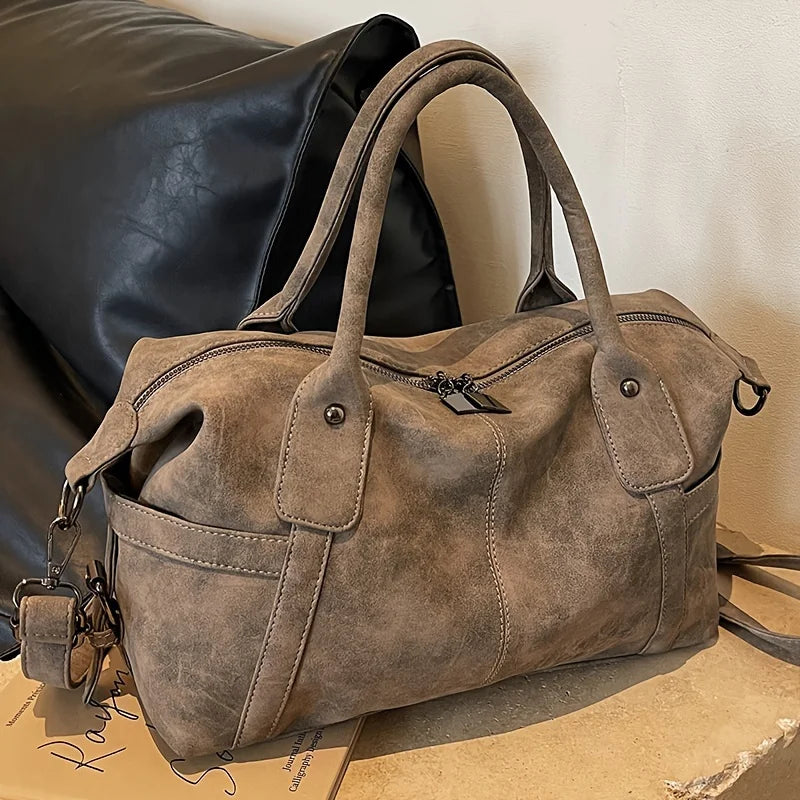 Cuir végan nubuck brun taupe sur un polochon souple posé de trois quarts, breloque au flanc gauche