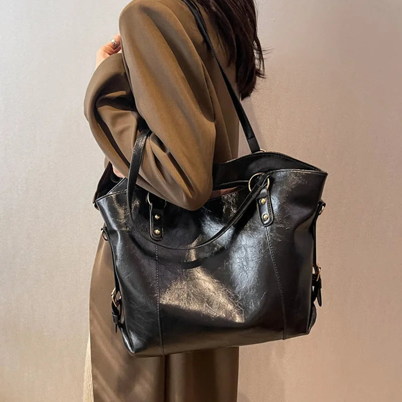 Porté à l'épaule sur un manteau taupe, le grand cabas noir s'écrase en larges plis lustrés
