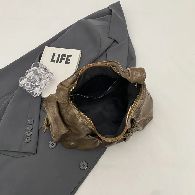 Intérieur noir du sac ouvert, glissière dorée en arc et poche plaquée contre la doublure