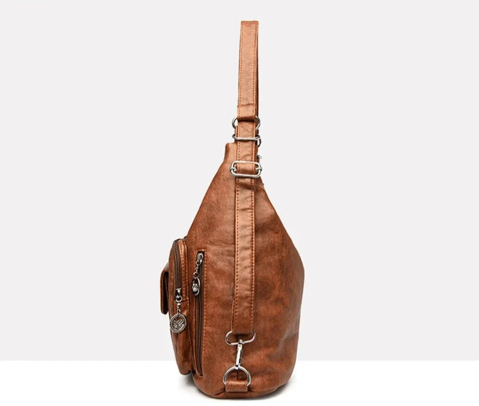 De profil, le hobo cognac montre sa poche zippée latérale et sa sangle à boucles métalliques