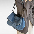 Chaîne tressée sur l'épaule, le sac en denim clair se cale contre un blazer taupe boutonné