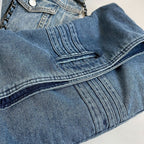 Détail du denim et de ses surpiqûres, plis marqués et petite patte cousue sur le rabat