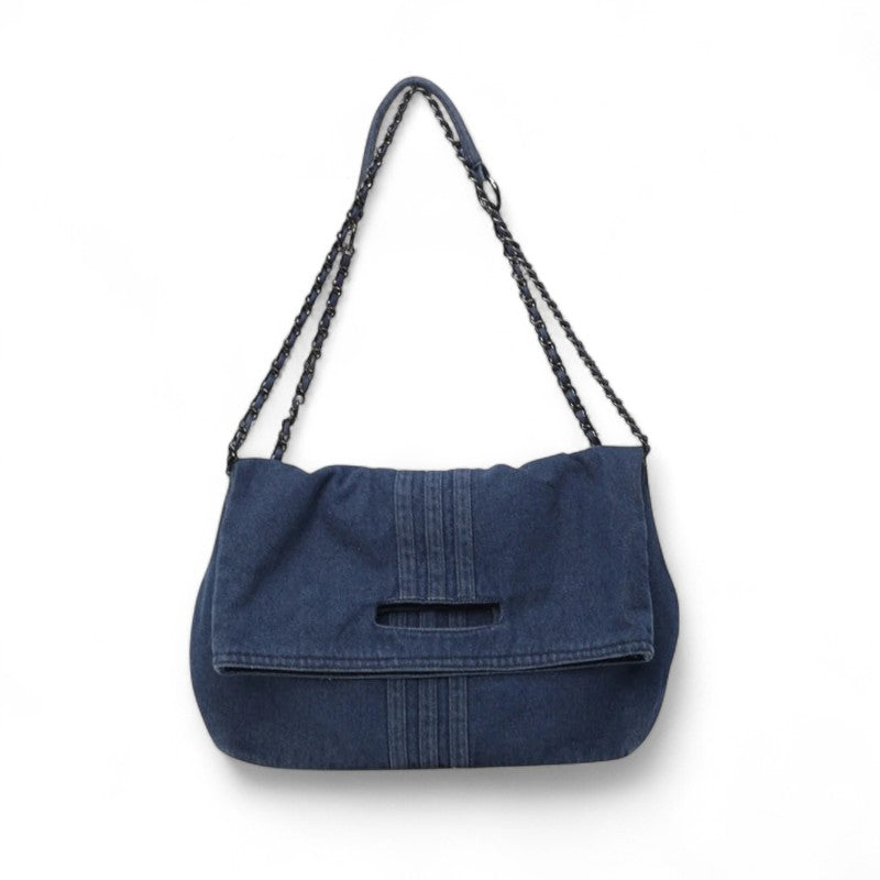Denim indigo foncé pour cette besace présentée de face, rabat souple et anse chaîne assortie