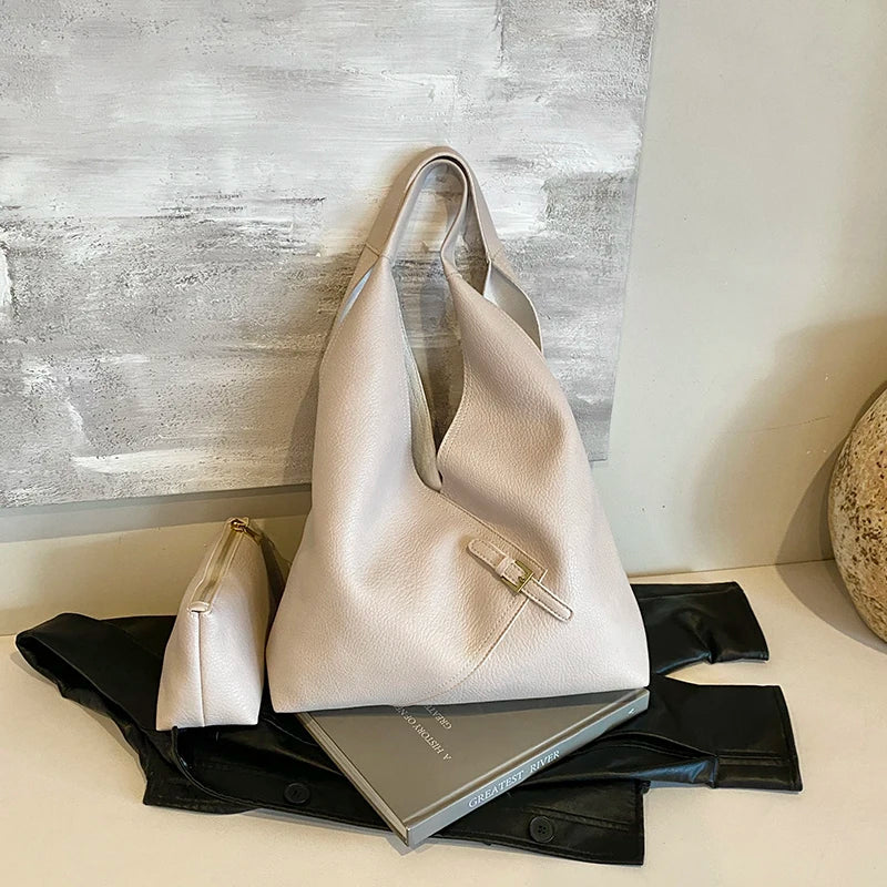 Duo beige rosé, grand sac et petite pochette alignés devant un panneau peint gris clair