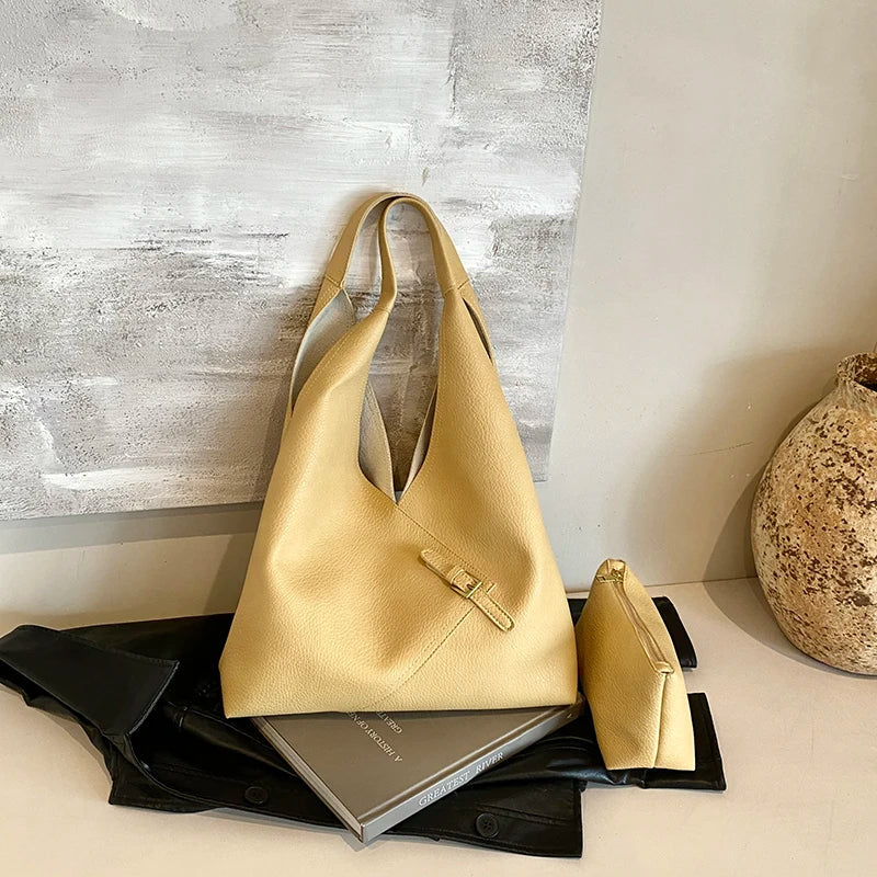 Ensemble jaune moutarde, hobo et pochette assortie devant une toile grise et un vase clair