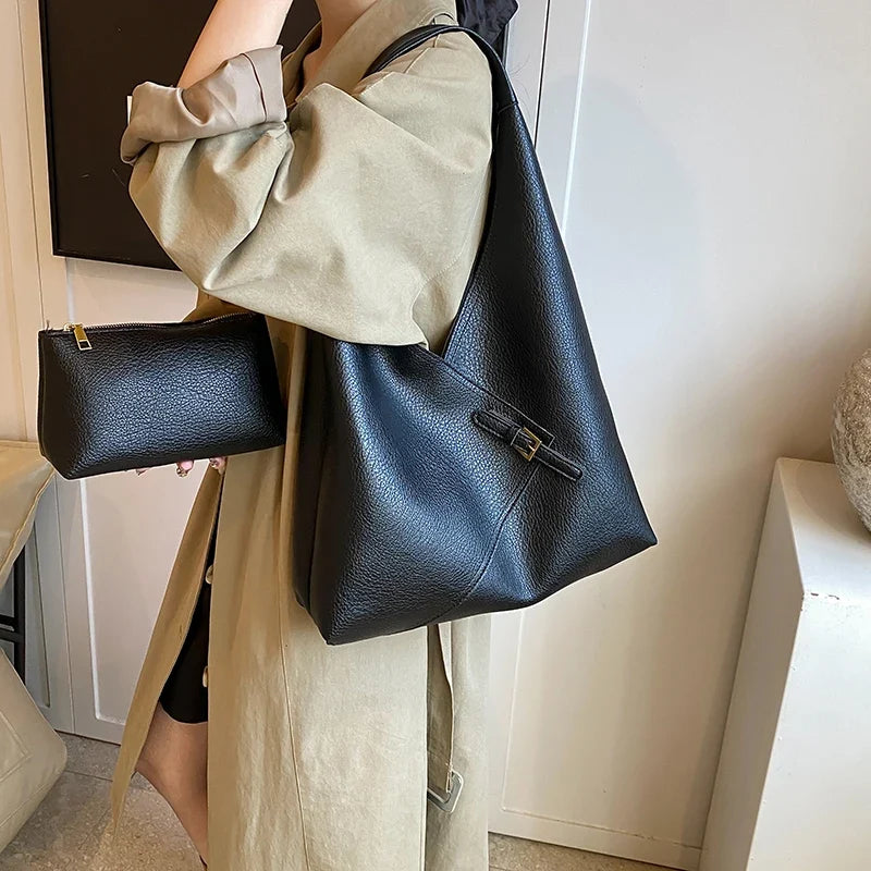 Porté à l'épaule sur un manteau beige, le hobo noir s'accompagne de sa pochette assortie