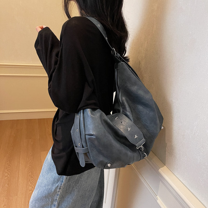Épaulé sur un haut noir, le modèle bleu gris s'affaisse en croissant contre la hanche