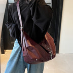 De dos, la large sangle traverse le buste et le sac bordeaux repose bas sur la hanche