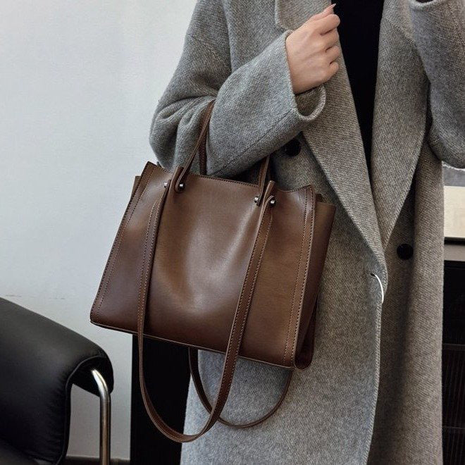 Tenu à la main devant un manteau gris, le cabas brun café garde ses angles bien droits