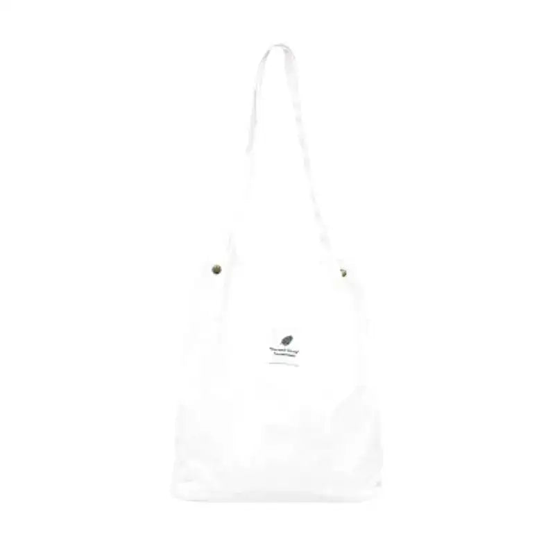 Tote bag blanc en toile côtelée, vu de face sur fond clair, petit écusson brodé au centre