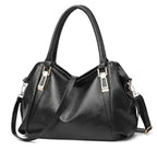 Sac à main noir en cuir végan souple, deux anses rondes, bandoulière amovible et plaques métal