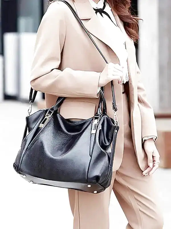 Au bras d'une femme en tailleur beige, le sac noir souple pend par ses anses dans la rue