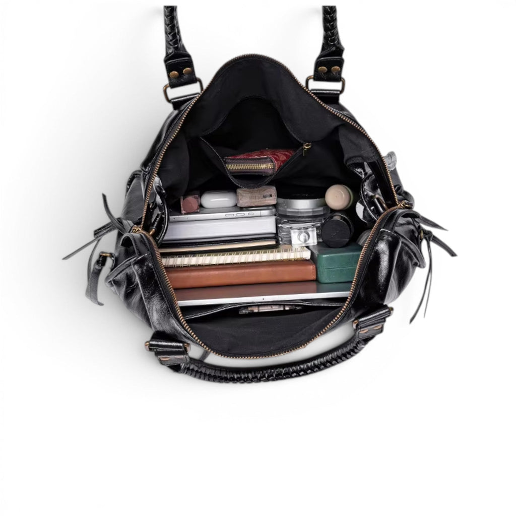 Plongée dans le sac ouvert, garni de cahiers, d'une trousse et de produits de beauté rangés debout
