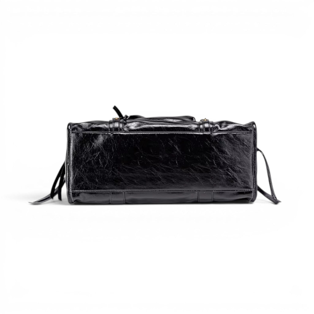 Dessous du sac noir, base rectangulaire renforcée et lanières de cuir végan retombant sur les côtés