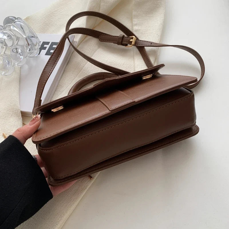 Dessus du sac chocolat, sangle réglable à coulisse et tranche de rabat surpiquée visibles