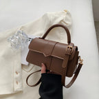 Boucle latérale dorée et cuir végan cacao, le sac se présente de face, bandoulière pendante