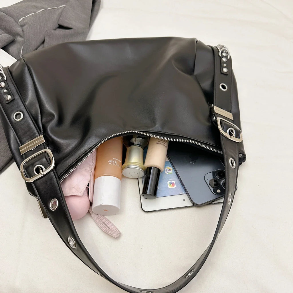 Ouverture zippée du sac noir, trousse rose, flacons de soin et téléphone glissés à l'intérieur