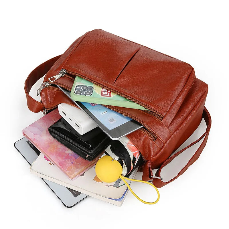 Contenu déballé du sac brun roux : tablette, téléphone, batterie, portefeuille et carnets