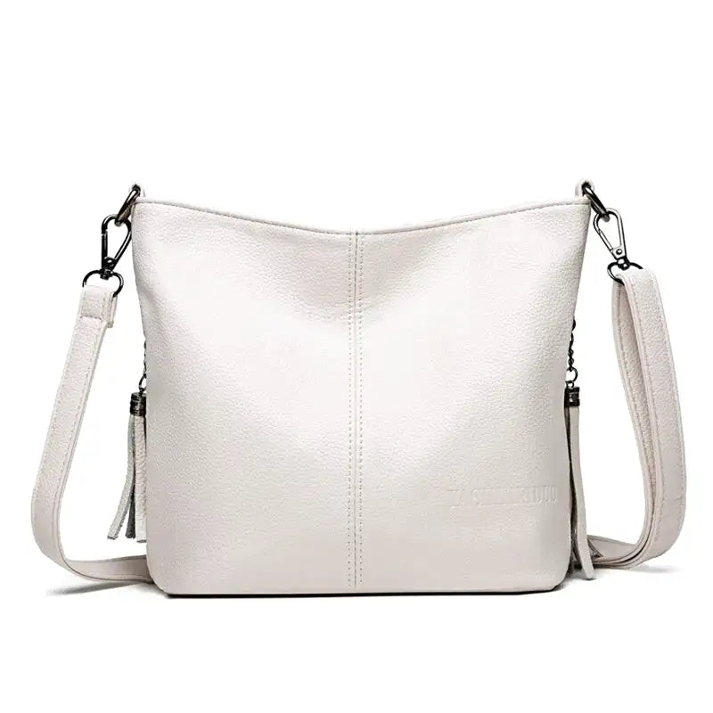 Petit sac seau blanc cassé à couture centrale, vu de face, anse d'épaule réglable et breloque frangée