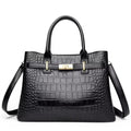 Sac à main structuré noir façon croco, de face, fermoir tournant doré et bandoulière fine
