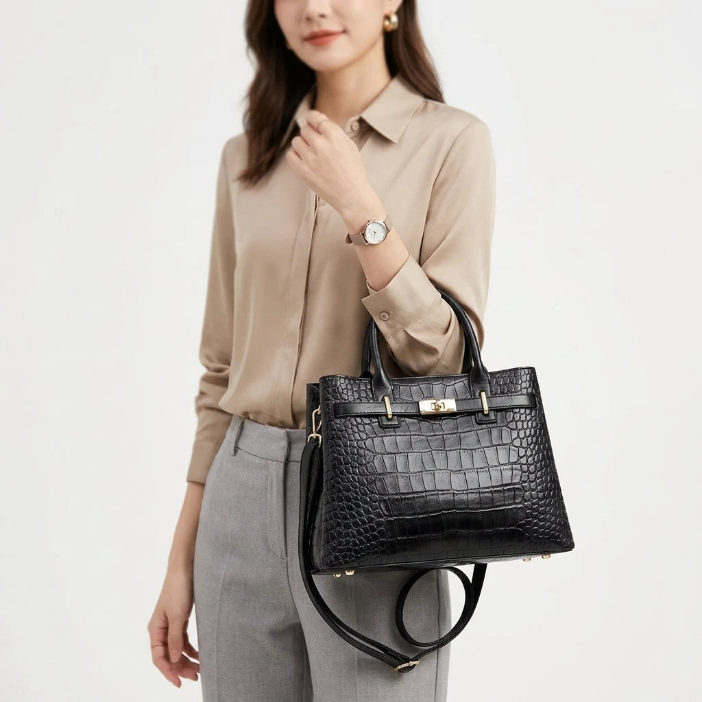 Tenu à la main devant un chemisier beige, le sac noir façon croco garde sa forme rigide