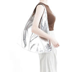 Épaule portant le hobo argent brillant, débardeur brun et pantalon blanc en arrière-plan clair