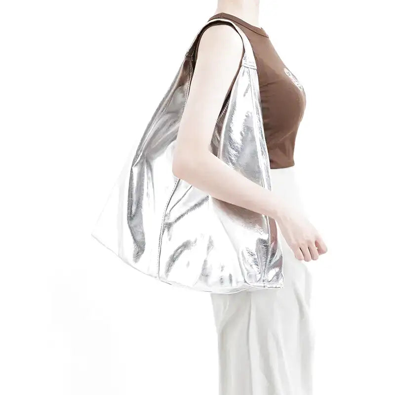 Épaule portant le hobo argent brillant, débardeur brun et pantalon blanc en arrière-plan clair