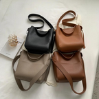 Quatre coloris du sac seau réunis à plat : noir, cognac, taupe et brun, sangles étalées
