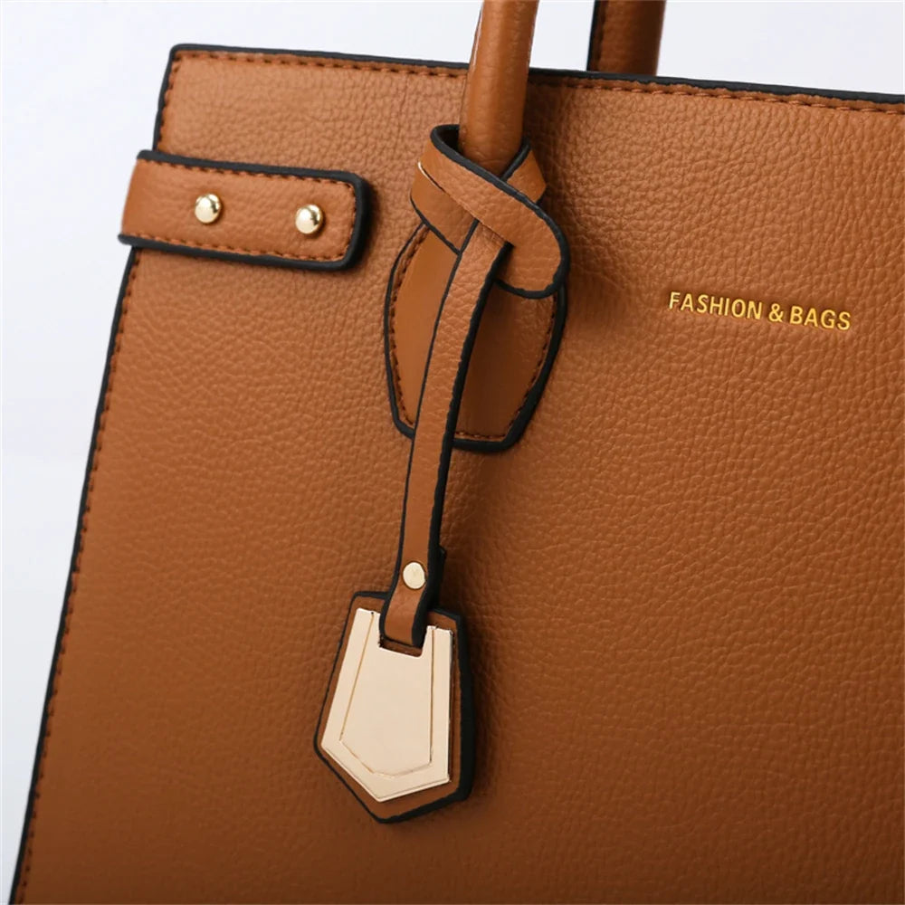 Détail de la breloque bicolore et du passant noué sur le flanc grainé du sac cognac