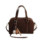 Sac bowling en suédine marron, deux anses courtes, bandoulière amovible et breloque baseball