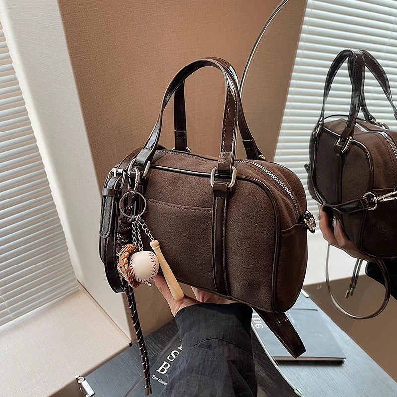Tenu à la main devant un miroir, le sac bowling marron s'y reflète avec sa breloque baseball