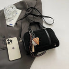 Mis en scène sur une veste grise avec un téléphone, le sac bowling noir et son bijou baseball