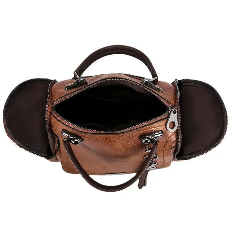 Ouverture zippée du sac cognac prise en plongée, doublure sombre et flancs latéraux dépliés