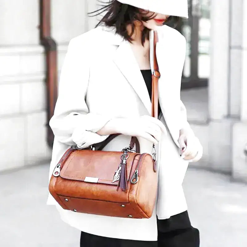 Sur un blazer blanc, le sac cognac se porte au creux du bras, bandoulière posée en travers
