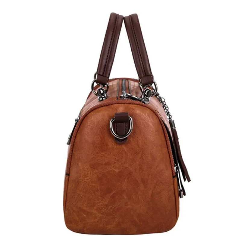 Flanc du sac cognac, anneau en D, glissière latérale et pompon suspendu à son attache